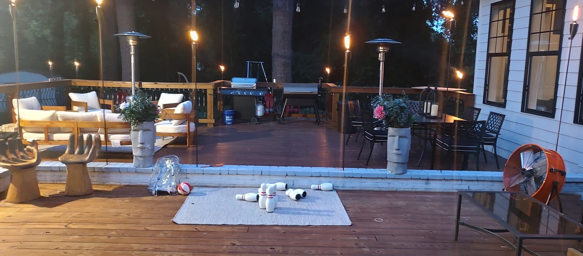 Large stained deck at dusk with outdoor seating, a dining set and string lights