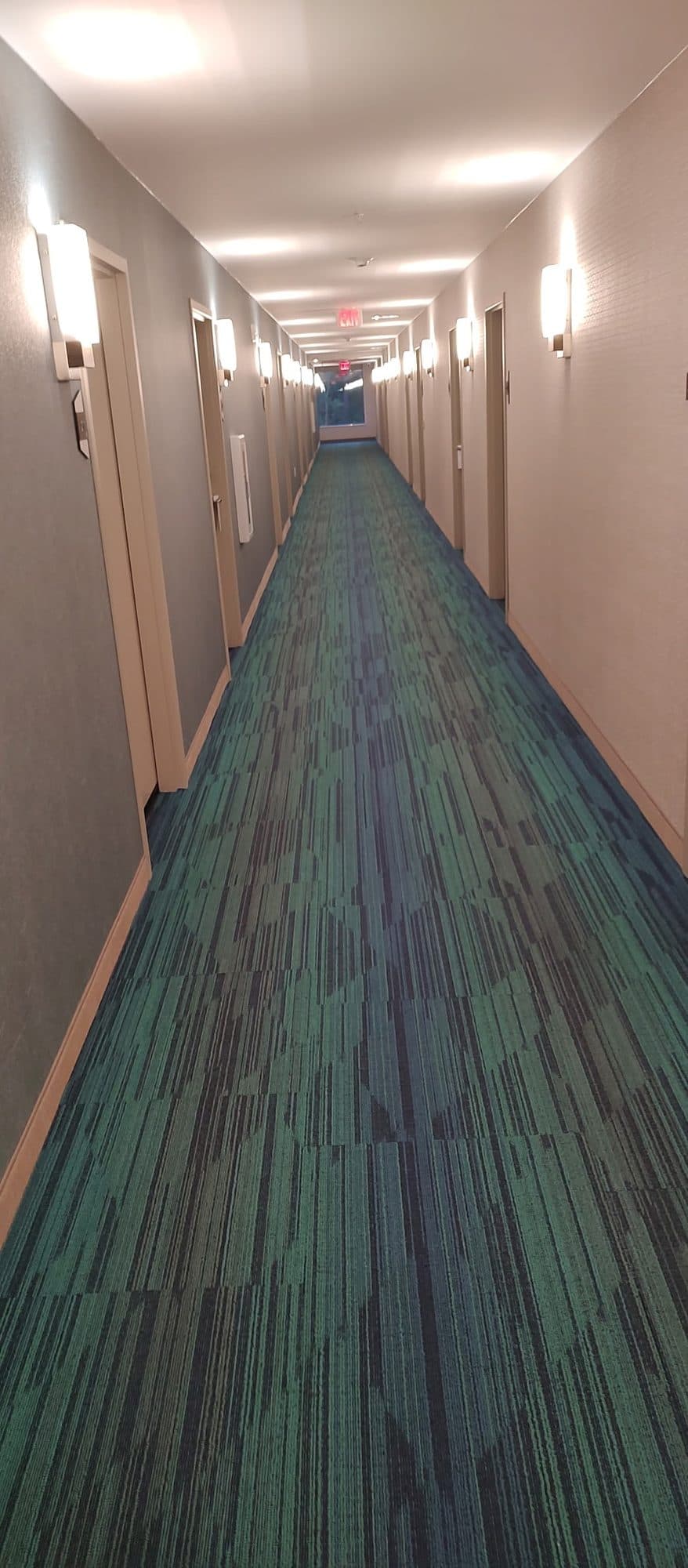 Long hotel corridor with patterned carpet and wall sconces