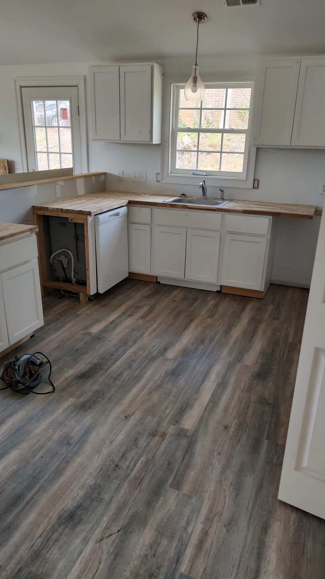 Remodeled kitchen with white shaker cabinets and gray plank flooring