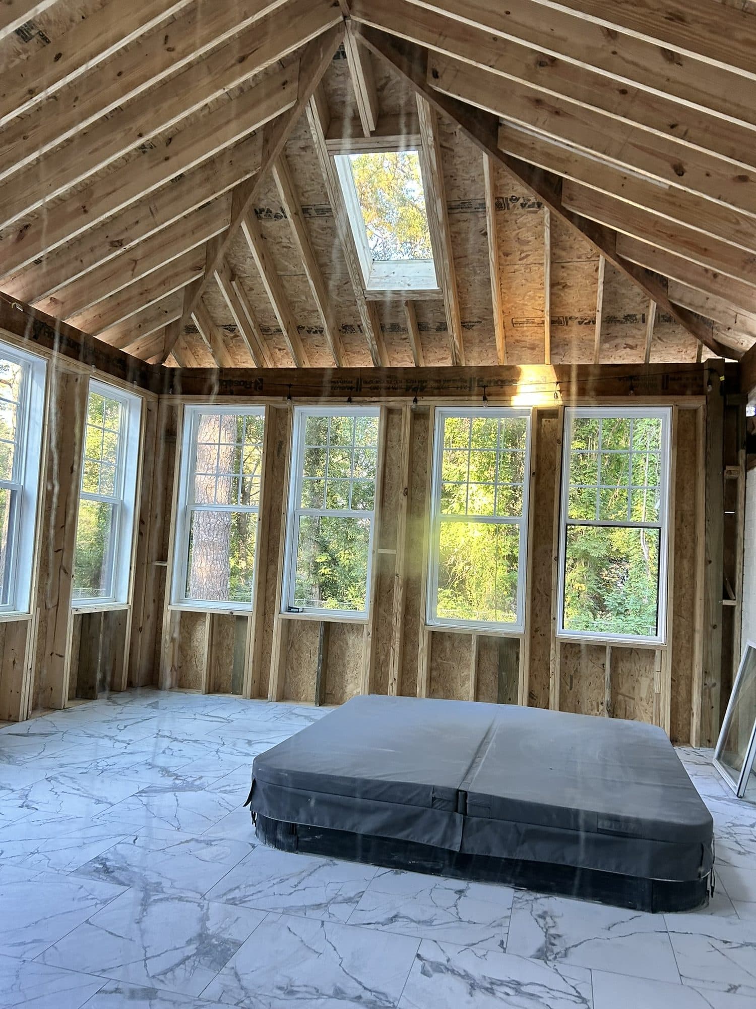 Framed sunroom addition with a vaulted ceiling, skylight and tall windows